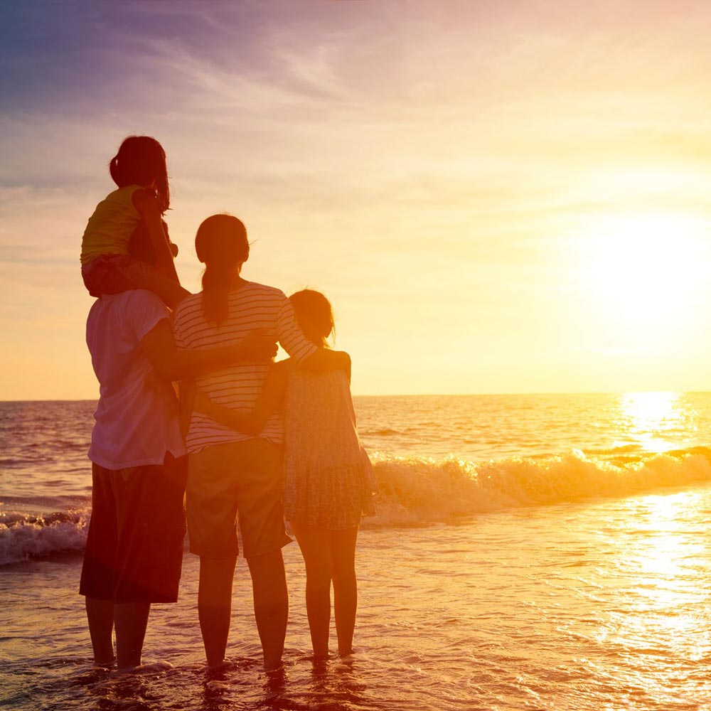 Happy family watching the sunset on the beach