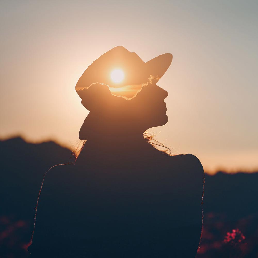 Silhouette of a woman with sunset overlay on her head