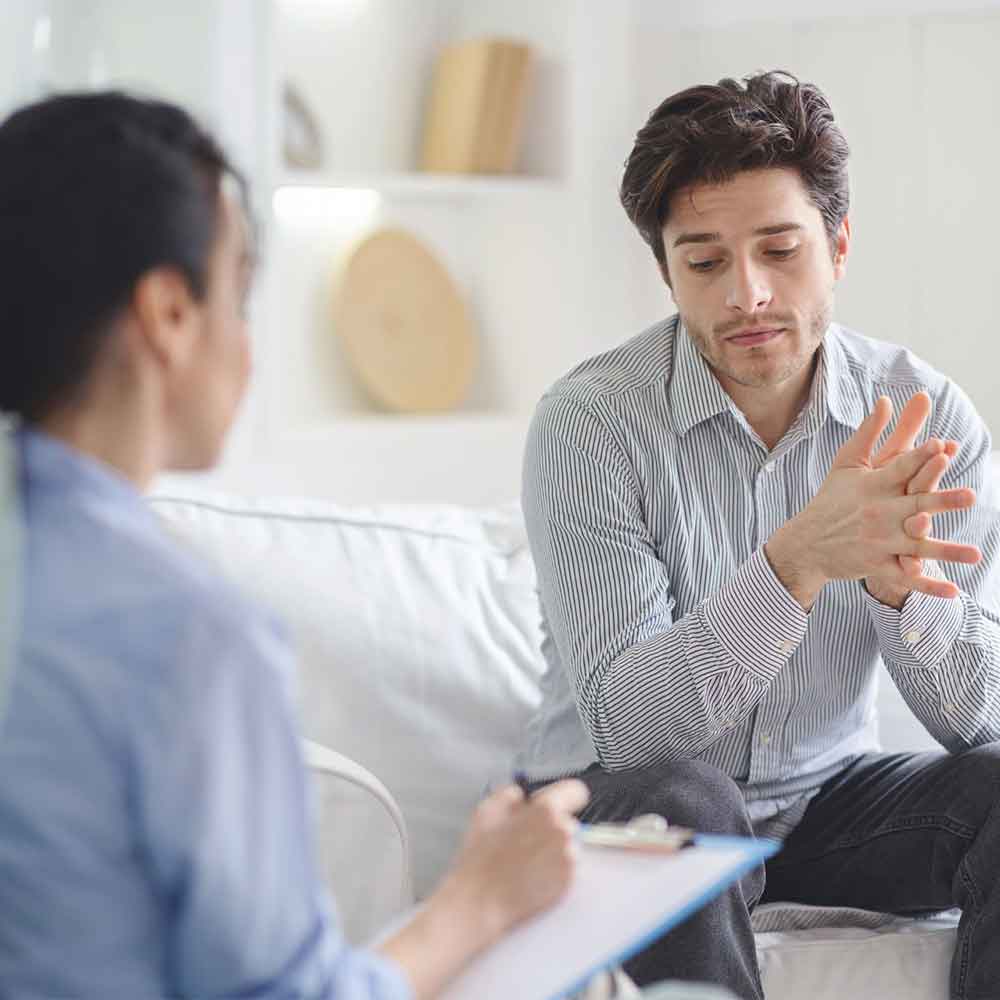 addiction therapist speaking with young adult male