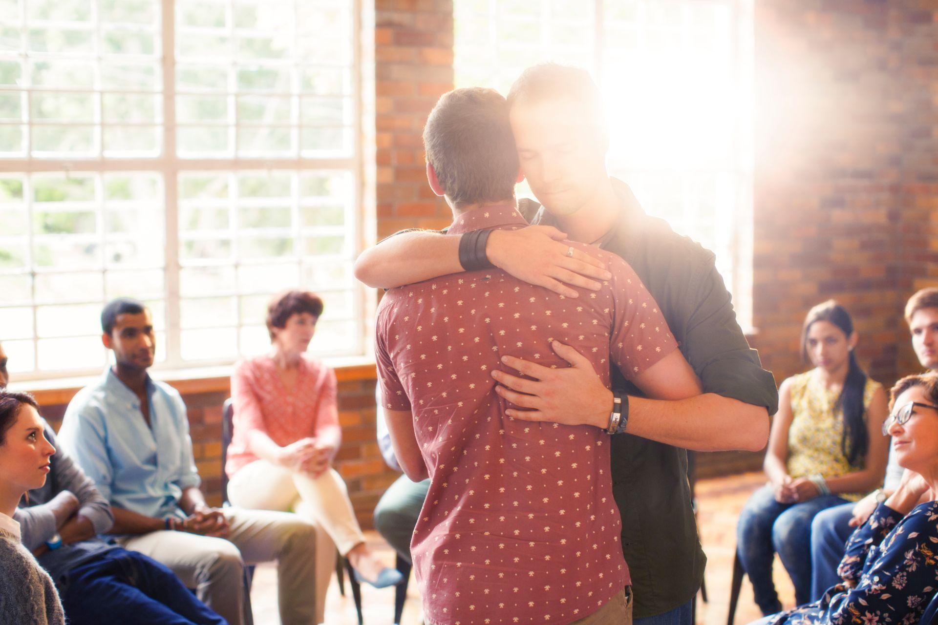 Men hugging at group therapy session