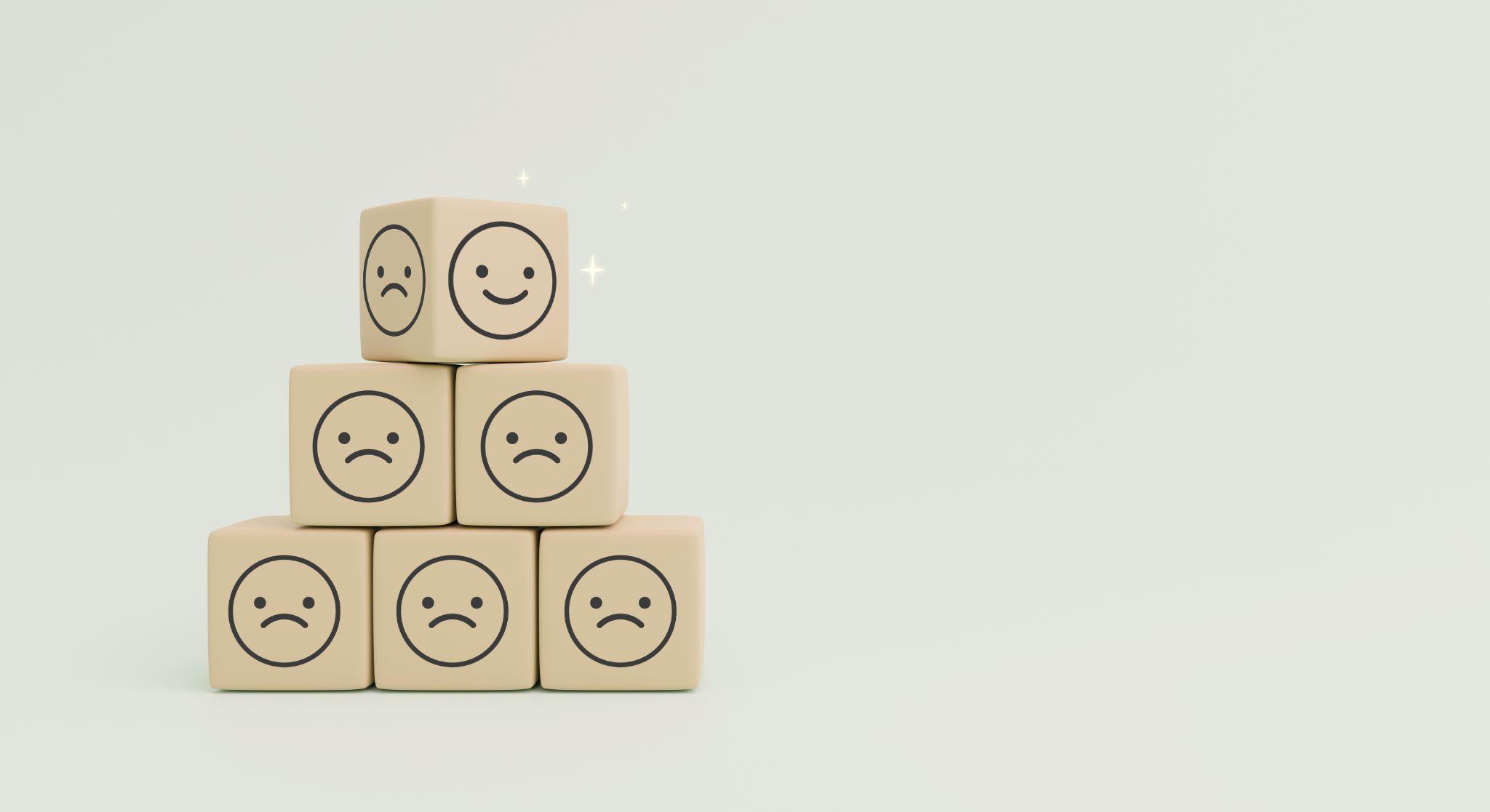 Wooden cubes of happy and sad face emotions