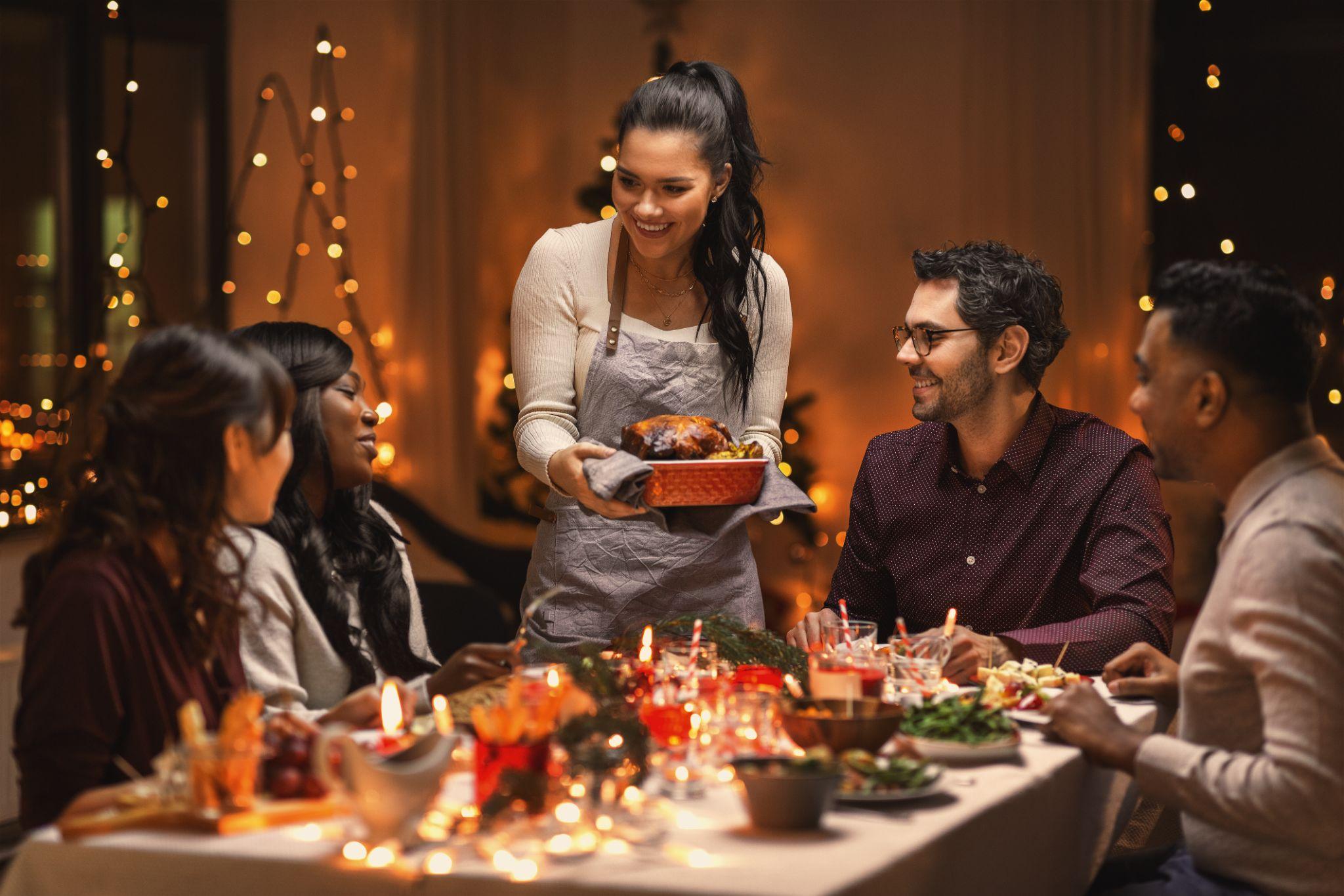 multiethnic group of happy friends having christmas dinner at home