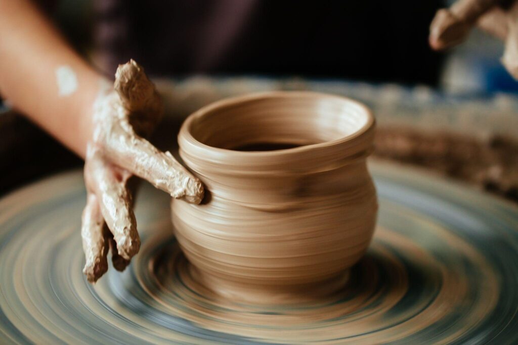 The potter's hands formed by a clay pot on a potter's wheel. 
