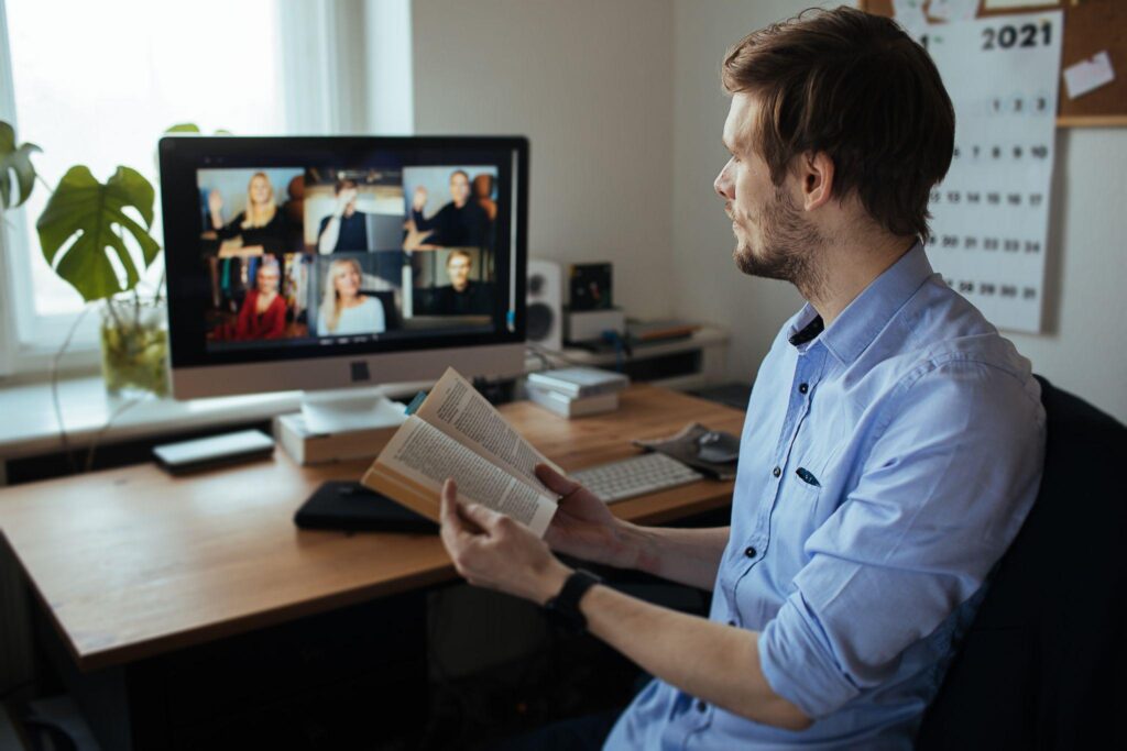 young man in reading a book in a video conference call